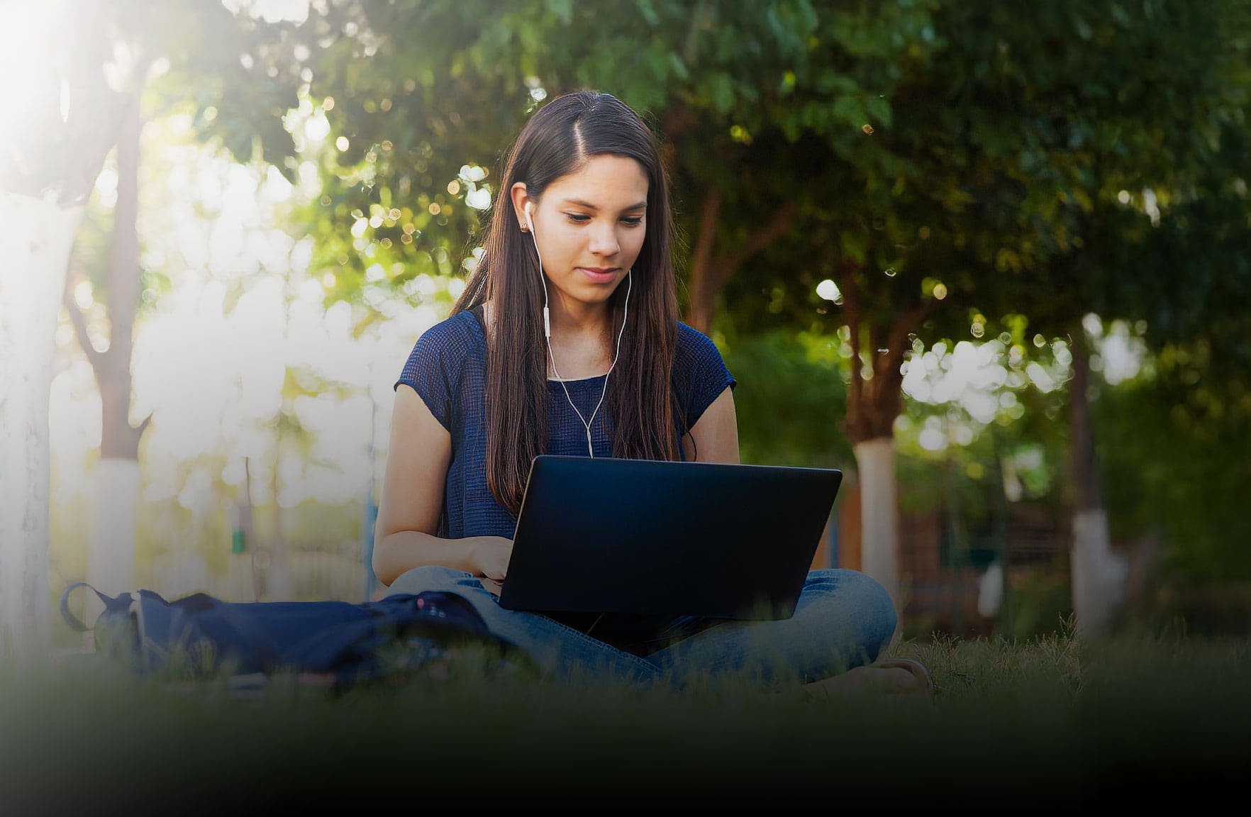 Student sitting outside on laptop taking virtual online classes
